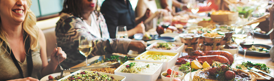 people sitting at a table sharing a common meal of vibrant foods